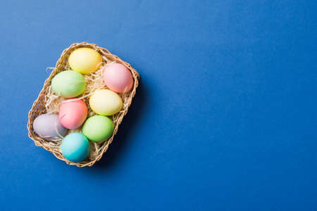 Multi colors Easter eggs in the woven basket on colored background . Pastel color Easter eggs. holiday concept with copy space.の写真素材