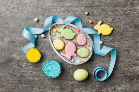 Colorful easter cookies in basket with Multi colors Easter eggs on colored background . Pastel color...