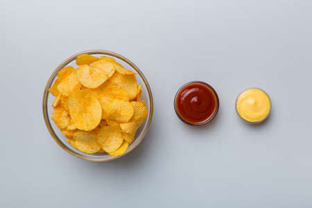 Top view chips with sause in bowl on colored background, top view with copy space.