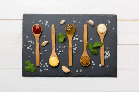 Different sauces in spoonson plate on table background, flat lay top view.