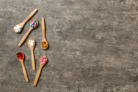 Top view Variety of vitamin and mineral pills in wooden spoon on Colored background. Top view of assorted pharmaceutical medicine pills. Dietary supplement healthcare product.の写真素材