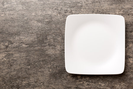 Top view of empty square plate on cement background. Empty space for your design.