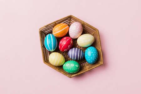 Multi colors Easter eggs in the woven basket on colored background . Pastel color Easter eggs. holiday concept with copy space.の写真素材