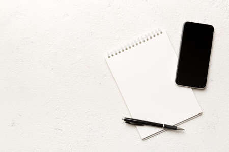 Smartphone with a notebook on a light Color background. top view.の写真素材