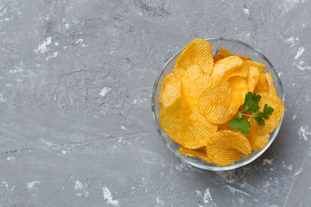 Potato chips on bowl with napkin on colored background. Delicious crispy potato chips in bowl. Space for text. top view.の写真素材