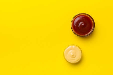 Bowl of ketchup and cheese sauce on colored background, top view with copy space.の写真素材