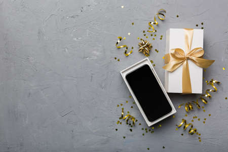 Opened gift box with gold ribbon and smartphone on color background, top view. Blank open box packaging mockup , Template for your design - branding mockup.の写真素材