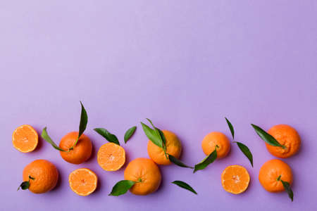 Many fresh ripe mandarin with green leaves on colored background, top view, space for text.
