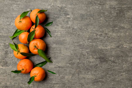 Many fresh ripe mandarin with green leaves on colored background, top view, space for text.の写真素材