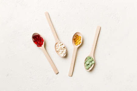 Top view Variety of vitamin and mineral pills in wooden spoon on Colored background. Top view of assorted pharmaceutical medicine pills. Dietary supplement healthcare product.の写真素材
