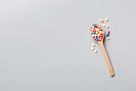 Vitamin capsules in a wooden spoon on a colored background. Pills served as a healthy meal. Drugs, pharmacy, medicine or medical healthycare concept.の写真素材