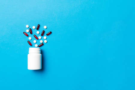 Multicolored pills and capsules in plastic bottle on Colored background, copy space. Many different various medicine tablets and pills, vitamin and nutritional supplements concept.の写真素材