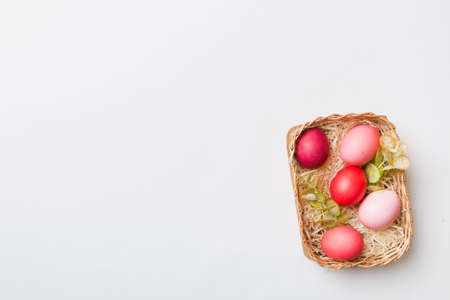 Multi colors Easter eggs in the woven basket on colored background . Pastel color Easter eggs. holiday concept with copy space.の写真素材