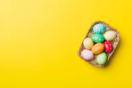 Multi colors Easter eggs in the woven basket on colored background . Pastel color Easter eggs. holiday concept with copy space.の写真素材