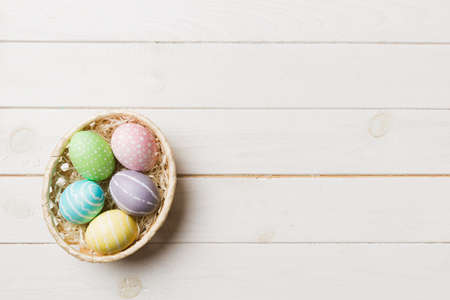 Multi colors Easter eggs in the woven basket on colored background . Pastel color Easter eggs....