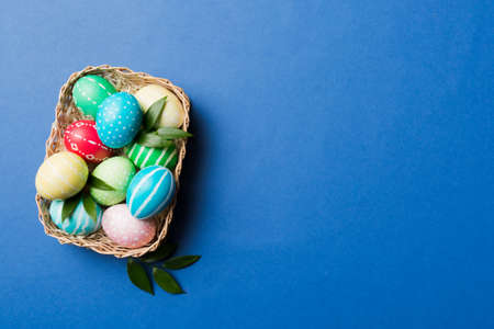 Multi colors Easter eggs in the woven basket on colored background . Pastel color Easter eggs. holiday concept with copy space.の写真素材