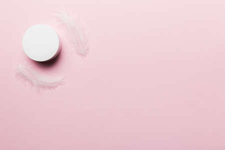 Set of skin care serums on pink pastel background with ostrich feathers. Spa cosmetic product, cream jar, branding mock up, top view with copy space.の写真素材
