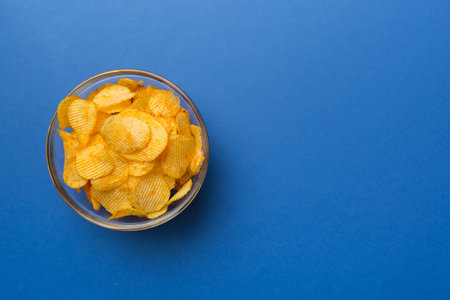 Potato chips on bowl isolated on colored background. Delicious crispy potato chips in bowl. Space for text. top view.の写真素材