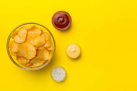 Top view chips with sause in bowl on colored background, top view with copy space.