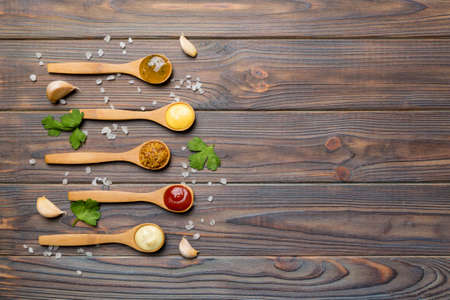 Different sauces in spoons on table background, flat lay top view.