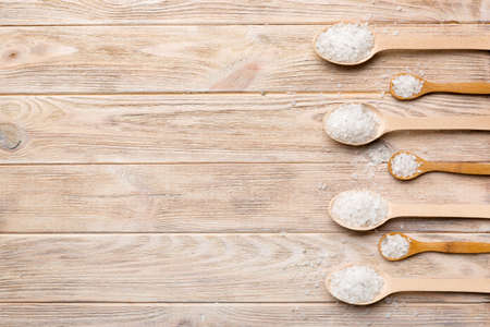 salt on wooden spoon on wood background. Spoons with different salt.の写真素材