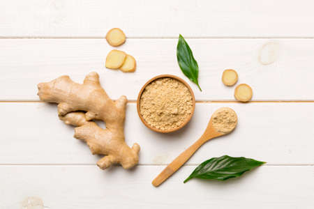 Finely dry Ginger powder in bowl with green leaves isolated on colored background. top view flat lay.の写真素材