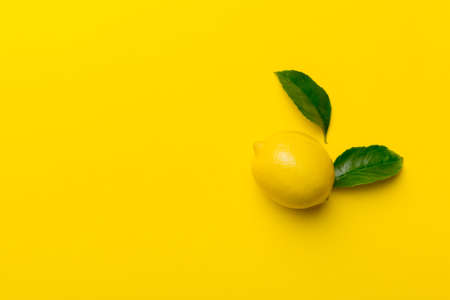 Many fresh ripe lemons with green leaves on colored background, top view, space for text.の写真素材