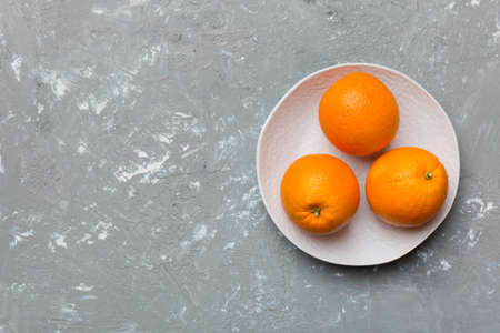 Flat lay of Fresh orange fruit with sliced in plate on Colored background. Top view with copy space.