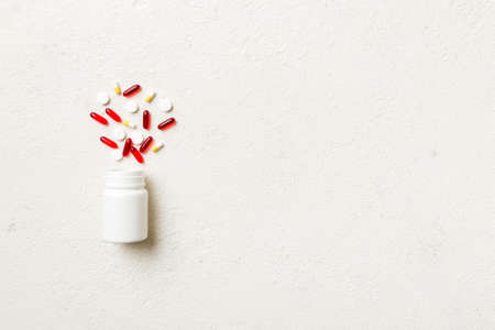 Multicolored pills and capsules in plastic bottle on Colored background, copy space. Many different various medicine tablets and pills, vitamin and nutritional supplements concept.の写真素材