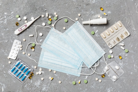 Protective face masks or surgical masks, medicine pills and thermometer on table background....