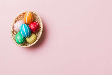 Multi colors Easter eggs in the woven basket on colored background . Pastel color Easter eggs....