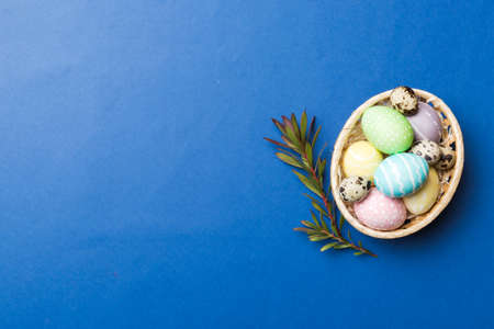 Multi colors Easter eggs in the woven basket on colored background . Pastel color Easter eggs....