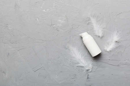 Set of skin care serums on pink pastel background with ostrich feathers. Spa cosmetic product, cream jar, branding mock up, top view with copy space.の写真素材