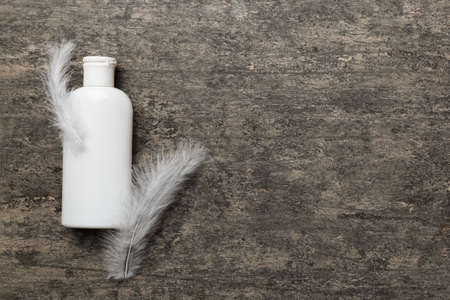 Set of skin care serums on pink pastel background with ostrich feathers. Spa cosmetic product, cream...
