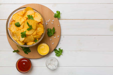 Top view chips with sause in bowl on colored background, top view with copy space.