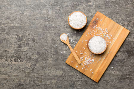 A wooden bowl of salt crystals on a wooden background. Salt in rustic bowls, top view with copy space.の写真素材
