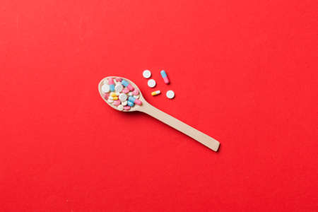 Vitamin capsules in a wooden spoon on a colored background. Pills served as a healthy meal. Drugs, pharmacy, medicine or medical healthycare concept.の写真素材