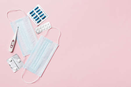 Protective face masks or surgical masks, medicine pills and thermometer on table background....