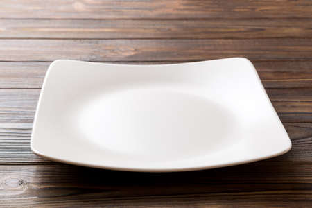 Perspective view of empty square plate on wooden background. Empty space for your design.の写真素材