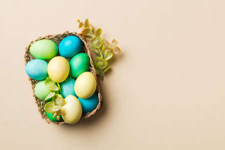 Multi colors Easter eggs in the woven basket on colored background . Pastel color Easter eggs....
