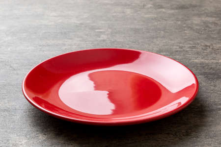 Perspective view of empty red plate on cement background. Empty space for your design.の写真素材