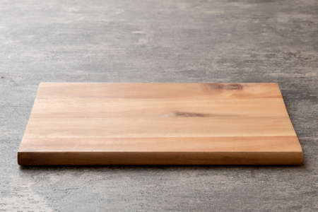 Perspective view of wooden cutting board on cement background. Empty space for your design.