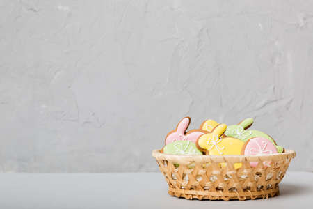 Colorful easter cookies in basket with Multi colors Easter eggs on colored background . Pastel color Easter eggs. holiday concept with copy space.の写真素材