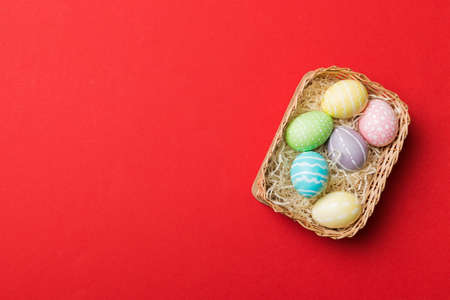 Multi colors Easter eggs in the woven basket on colored background . Pastel color Easter eggs. holiday concept with copy space.の写真素材