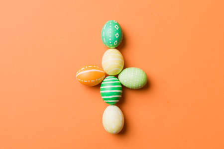 holiday preparation Multi colors Easter eggs on colored background, cross show the religious and secular side of Easter. Pastel color Easter eggs. holiday concept with copy space.の写真素材