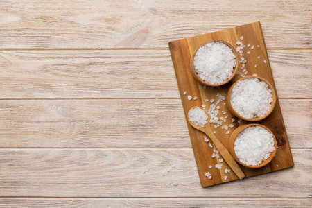 A wooden bowl of salt crystals on a wooden background. Salt in rustic bowls, top view with copy space.の写真素材
