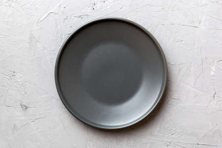 Top view of black plate on cement background. Empty space for your design.の写真素材