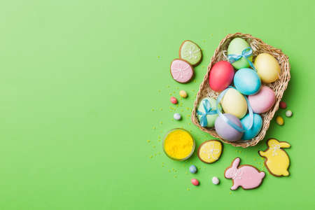 Colorful easter cookies in basket with Multi colors Easter eggs on colored background . Pastel color...