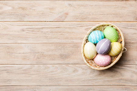 Multi colors Easter eggs in the woven basket on colored background . Pastel color Easter eggs....