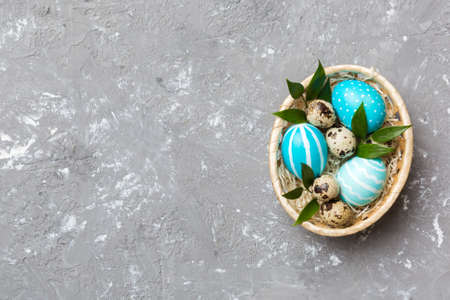 Multi colors Easter eggs in the woven basket on colored background . Pastel color Easter eggs....